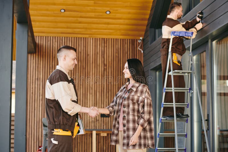 Cliente heureuse et employée de service de maintenance serrant la main images stock