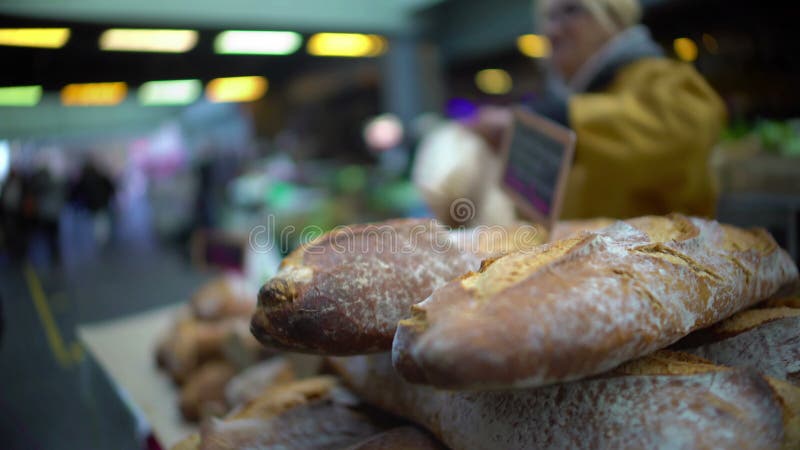 Cliente maschio che compra di recente pane al forno al mercato, allo stile di vita sano ed all'alimento