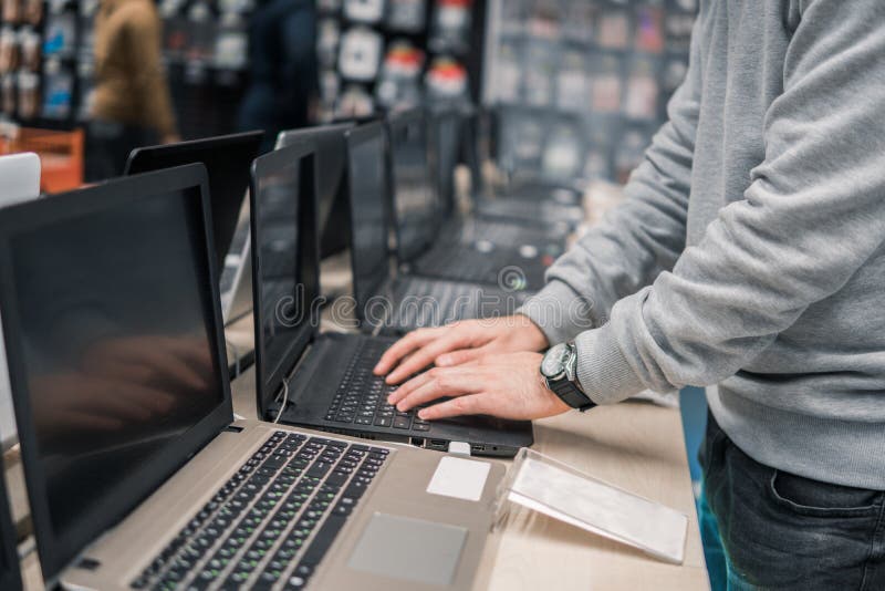 Cliente masculino moderno que escolhe o portátil na loja de informática foto de stock Cliente masculino moderno que escolhe o portátil na loja de informática foto de stock