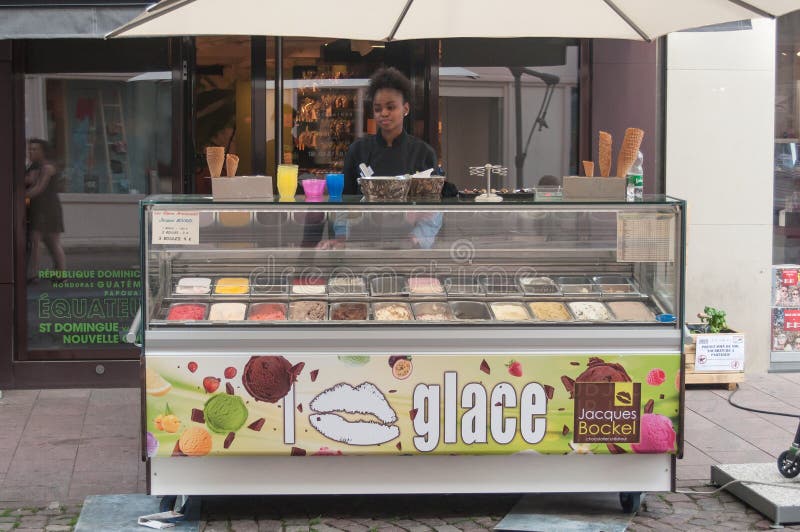 Cliente que espera joven de la mujer negra en Jacques Bockel el comerciante francés del helado en la calle fotos de archivo Cliente que espera joven de la mujer negra en Jacques Bockel el comerciante francés del helado en la calle fotos de archivo