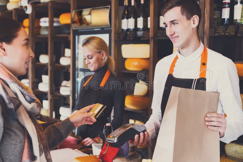 Cliente que paga pela ordem de queijo na loja de mantimento fotografia de stock Cliente que paga pela ordem de queijo na loja de mantimento fotografia de stock