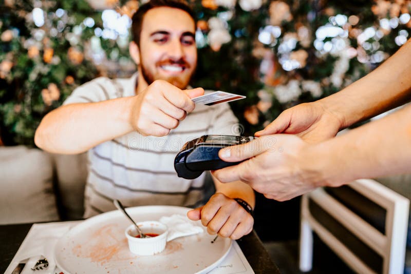 Cliente sorridente al ristorante che paga il pranzo con la carta di credito senza contatto Dettagli senza contatto di tecnologia immagini stock libere da diritti Cliente sorridente al ristorante che paga il pranzo con la carta di credito senza contatto Dettagli senza contatto di tecnologia immagini stock libere da diritti