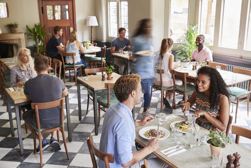 Clients appréciant des repas dans le restaurant occupé photo stock Clients appréciant des repas dans le restaurant occupé photo stock