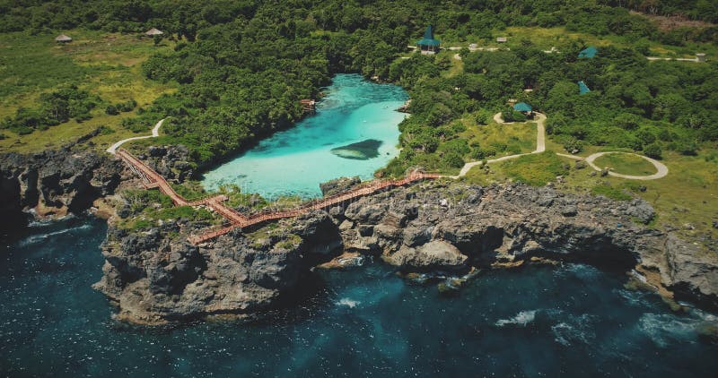 Cliff sea coastline with green landscape, limpid lake on top in aerial view. Scenic tropic seascape