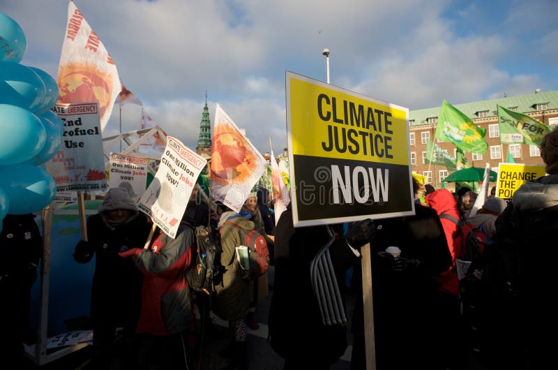 A climate change protester holds a sign that reads 'Climate Justice Now' during the COP15 climate summit in Copenhagen, Denmark. World climate change stock images, royalty-free photos and pictures