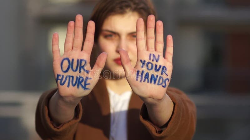 Climatic strike. Close portrait of a short-haired girl. The student holds her hands in front of her, the inscription on