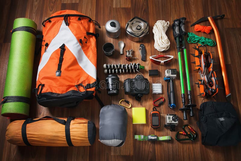 Climbing equipment: rope, trekking shoes, crampons, ice tools, ice ax, ice screws, red knife and other set on dark wooden backgrou