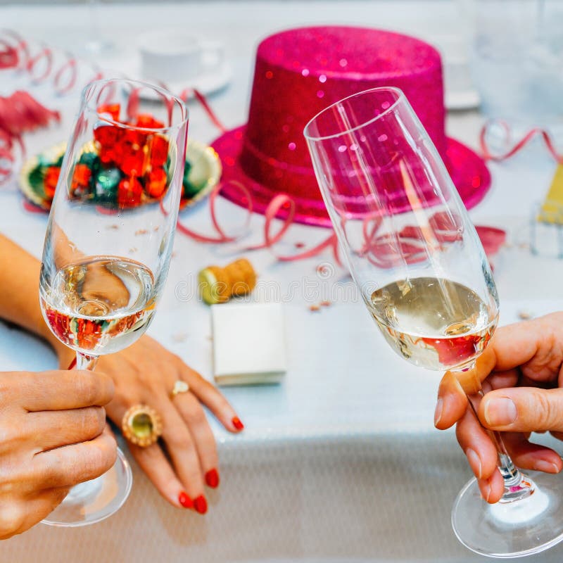Two Hands Clinking Champagne Glasses Over Blurred New Year Background