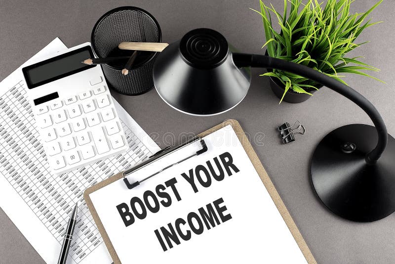 Clipboard ,chart and calculator, lamp and workspace accessories on a grey table. Top view , text BOOTS YOUR INCOME royalty free stock images