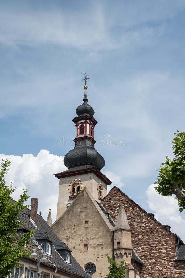 The clock tower of St Jakobus church is set against a partly cloudy sky. The architecture features a distinctive onion dome spire with multiple tiers and a crucifix at its peak. The foreground features traditional stonework, indicative of the region's historical construction methods. The clock tower of St Jakobus church is set against a partly cloudy sky. The architecture features a distinctive onion dome spire with multiple tiers and a crucifix at its peak. The foreground features traditional stonework, indicative of the region's historical construction methods