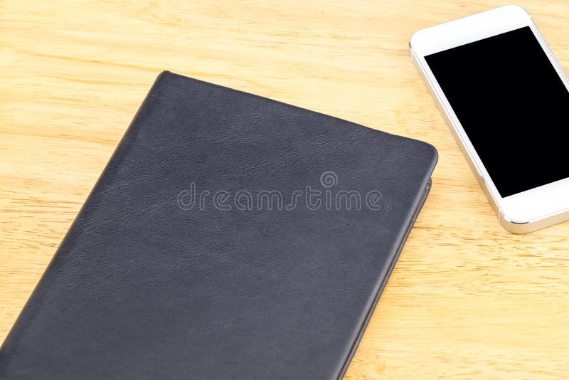 Close black blank notebook and mobile on wooden table,Mock up for adding your content stock photos