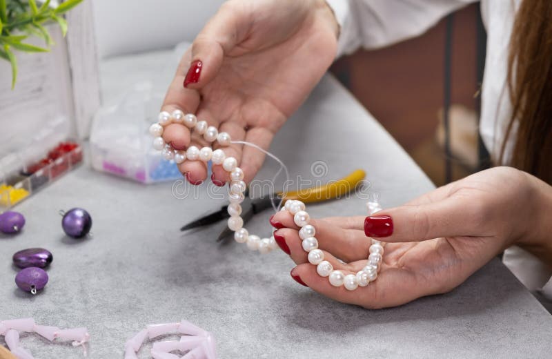 Close hand jeweler stringing pearls on a necklace. royalty free stock photography