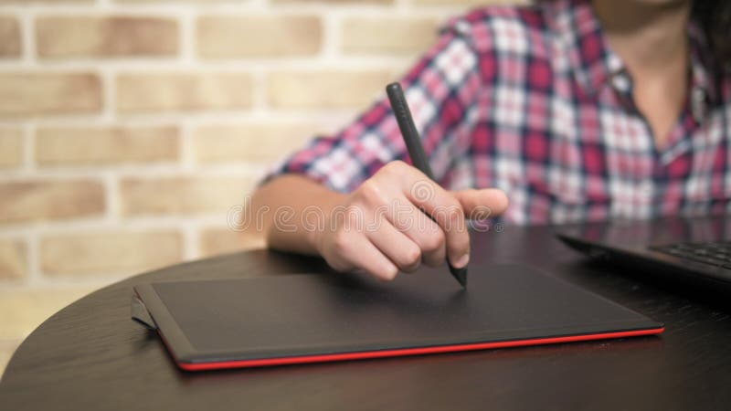 Close. Hand of a teenager boy in a plaid shirt using a stylus. works on a graphic tablet stock footage