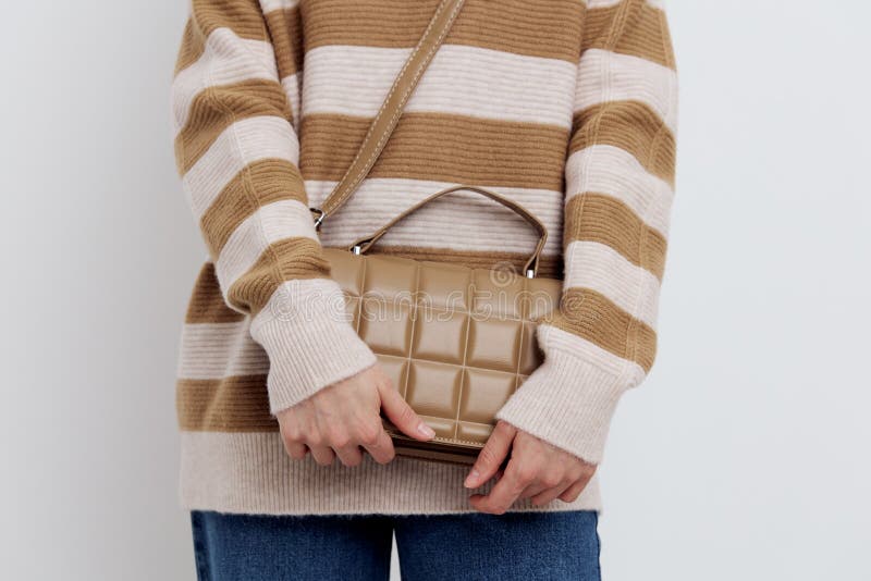 a close horizontal photo of a beautiful, stylish beige women& x27;s bag with a pattern in the form of squares, worn over