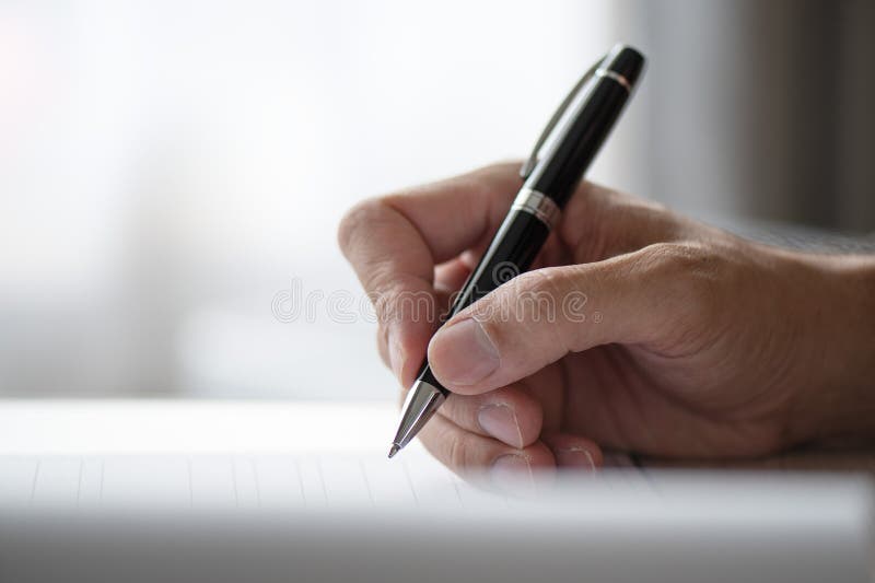 Close shot of a human hand writing something on the paper stock photography