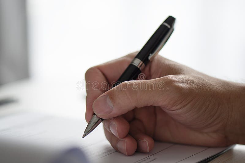 Close shot of a human hand writing something on the paper royalty free stock photo