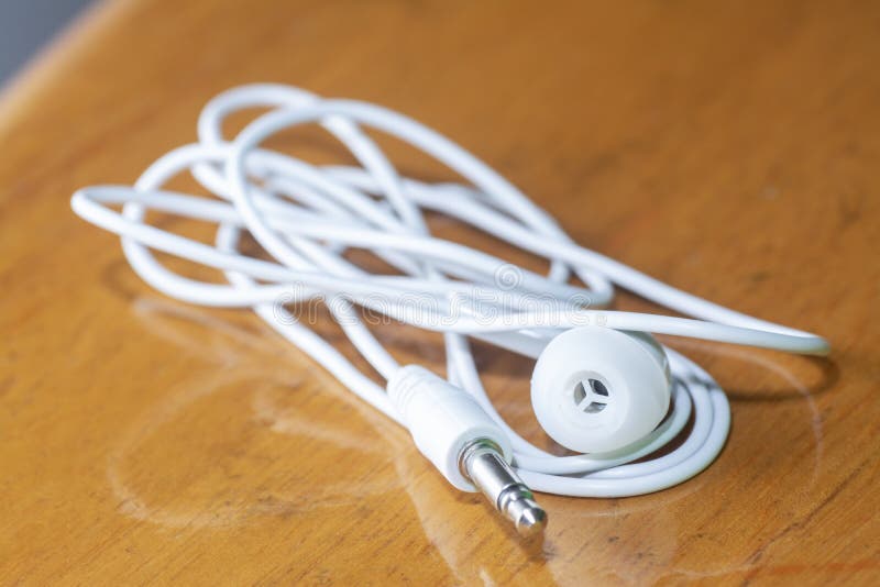 Close shot image of single lined white wired earphone plug. royalty free stock photography