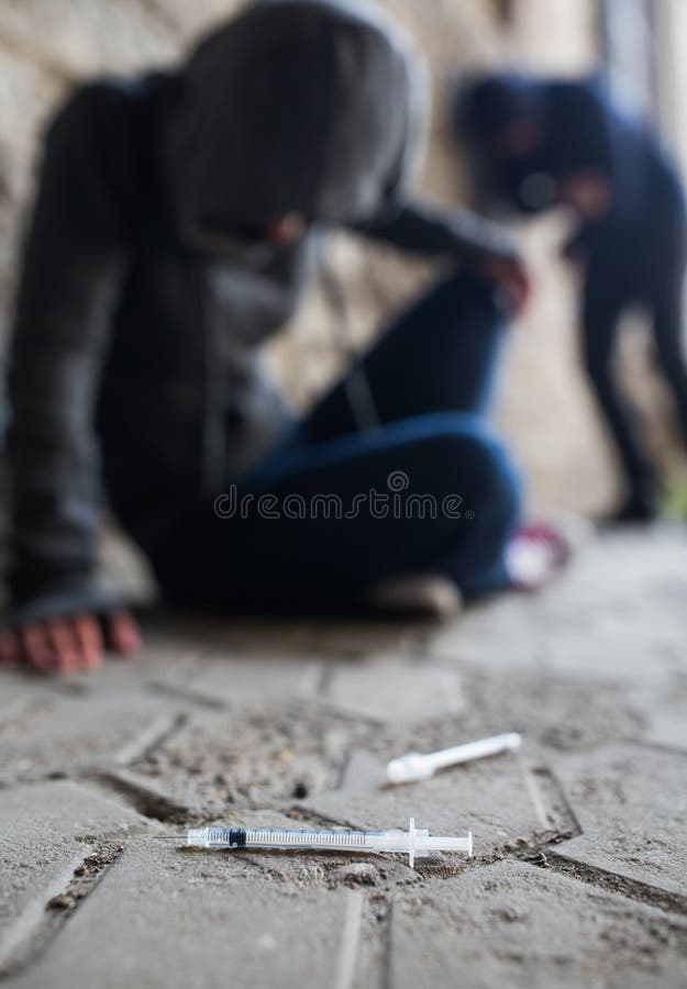 Substance abuse, addiction, people and drug use concept - close up of addicts and used syringes on ground. Substance abuse, addiction, people and drug use concept - close up of addicts and used syringes on ground