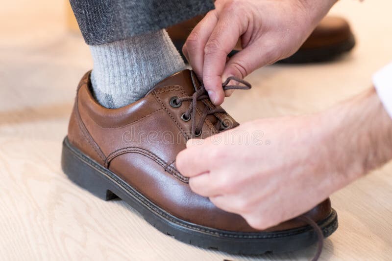 Close Up Of Adult Son Helping Senior Man Tie Shoelaces