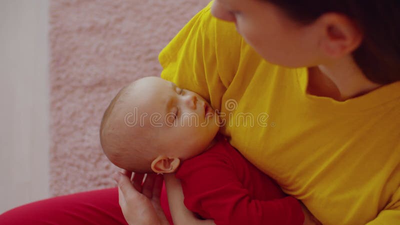 Affectionate mother holding and gently caressing sleeping infant baby