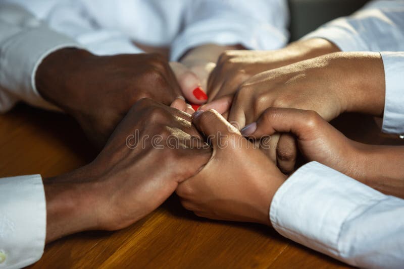 Close up of african-american and caucasian human`s hands holding on wooden table royalty free stock image