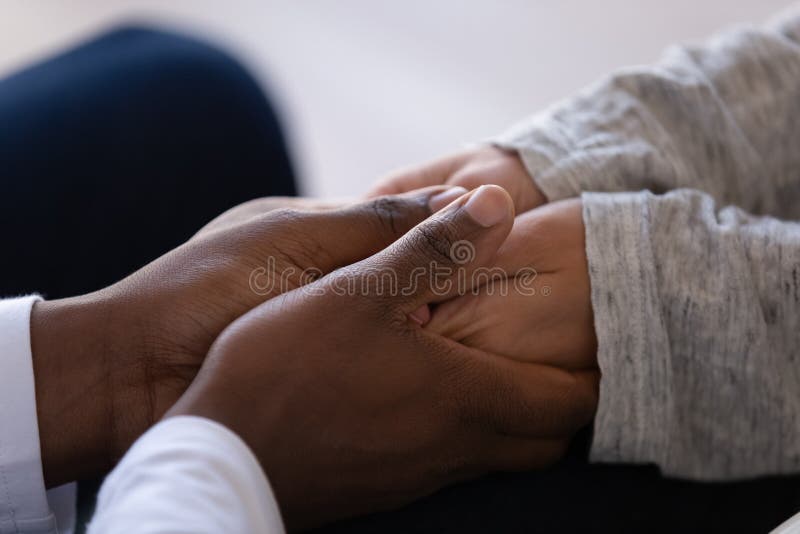 Close up African American men comforting woman, holding hands, saying sorry, showing love and support, caring husband calming wife, sympathy and compassion, understanding in relationships. Close up African American men comforting woman, holding hands, saying sorry, showing love and support, caring husband calming wife, sympathy and compassion, understanding in relationships