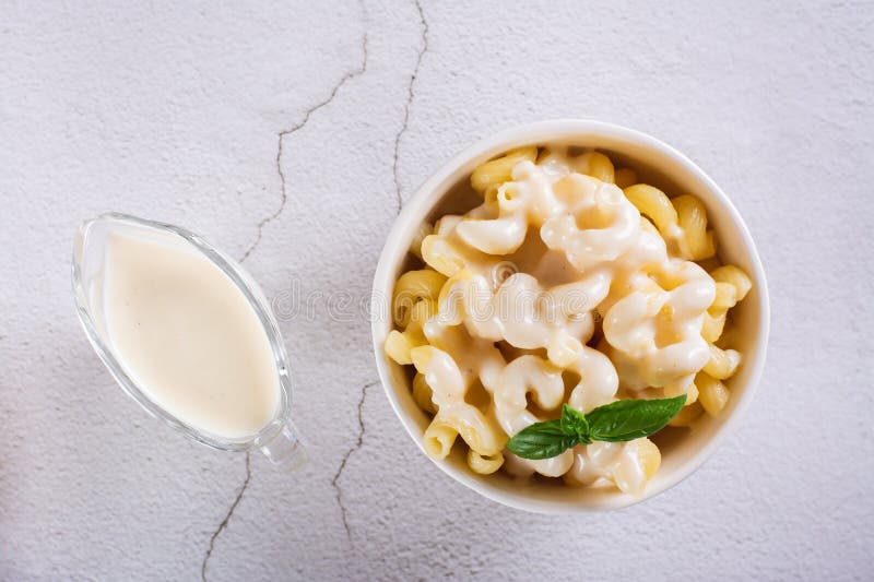Close up of appetizing pasta with cheese sauce and basil in a bowl on the table top view stock image