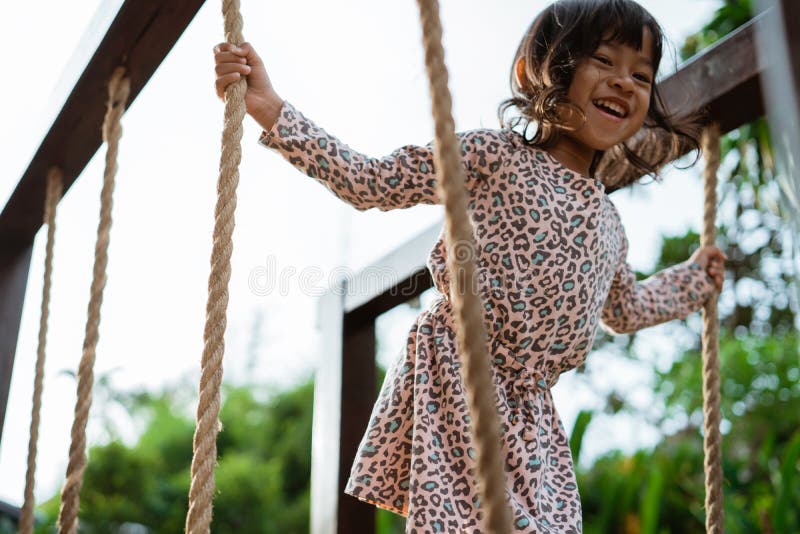 Close up of asian little girl smilling when hold the rope playing balance beam