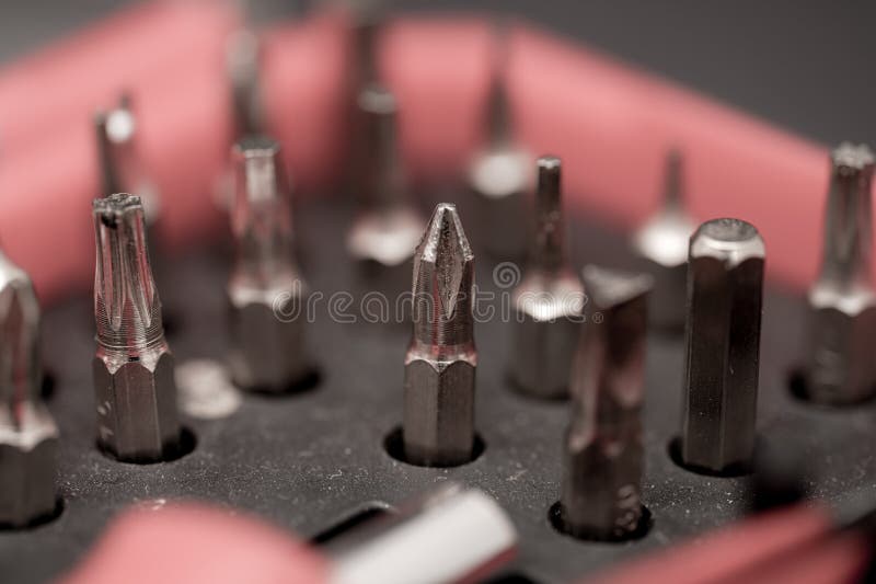 Close-up of assorted screwdriver bits arranged in a black holder on a dark surface showing different shapes and sizes stock photography