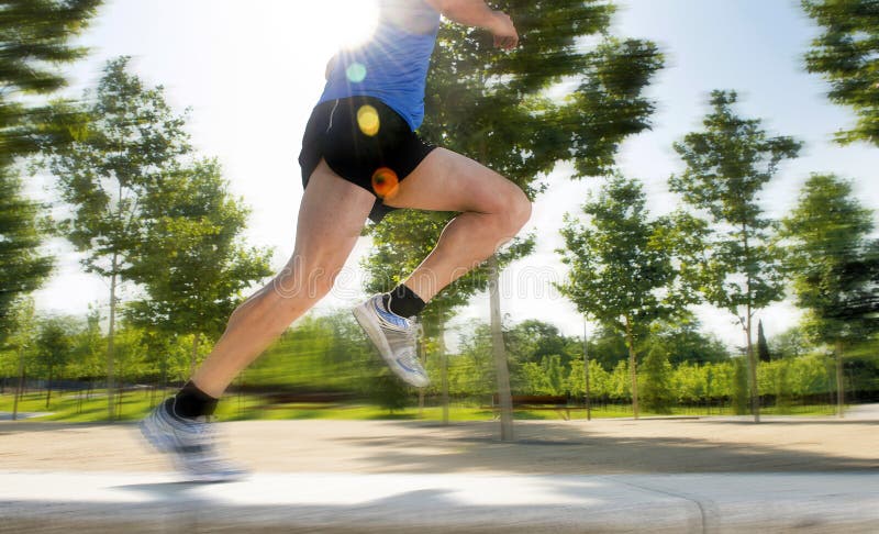 Close up athletic legs of young man running in city park on summer training in healthy lifestyle concept stock image Close up athletic legs of young man running in city park on summer training in healthy lifestyle concept stock image