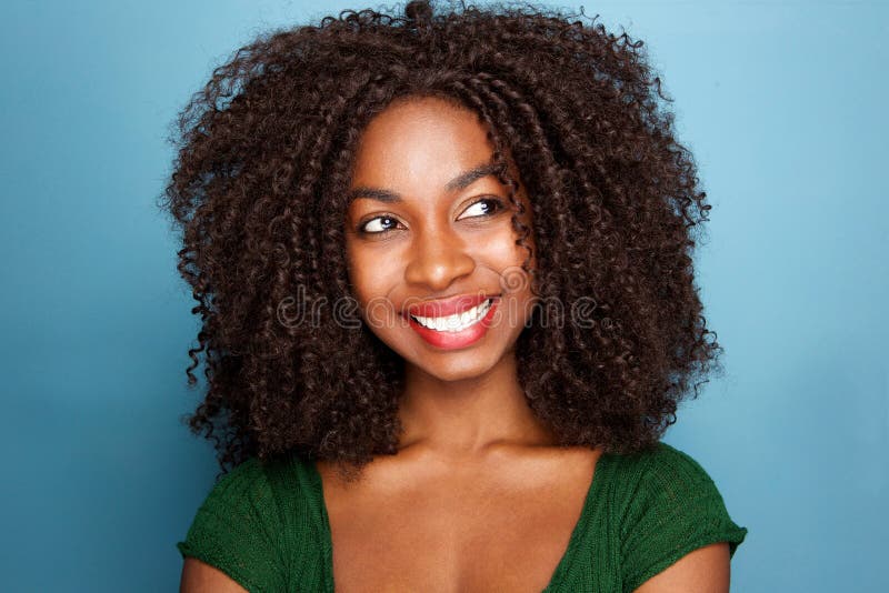 Close up attractive young african woman with curly hair looking away on blue background