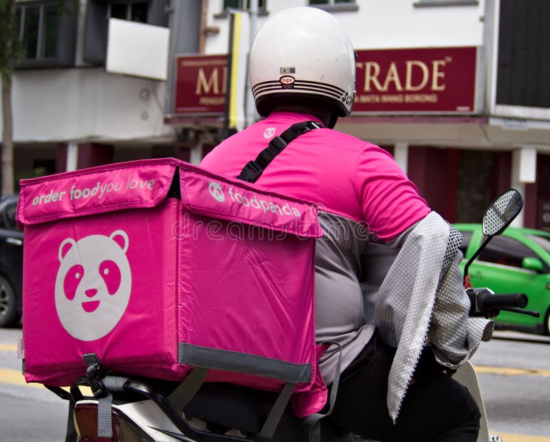 Close-up back view of a male Foodpanda delivery rider stopping at a busy traffic light junction in Ipoh, Malaysia. Close-up back view of a male Foodpanda delivery rider stopping at a busy traffic light junction in Ipoh, Malaysia