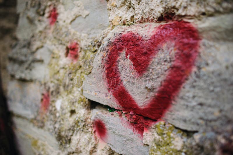 Close up background graffiti silhouette of red heart on an old relief stone wall