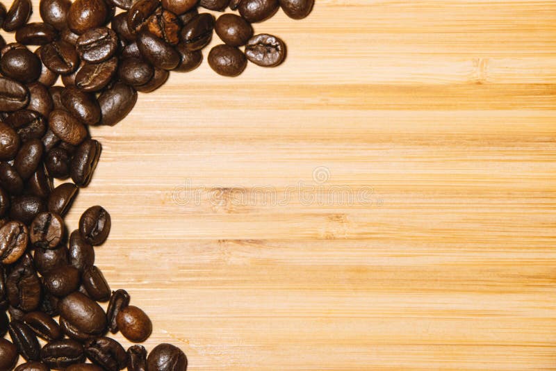 Close up of a bamboo board with roasted coffee beans on a side. Background concept