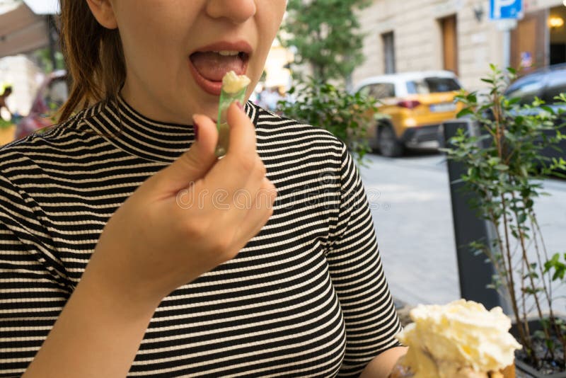 Close up of beautiful girl face of caucasian girl with red hair and open mouth eating ice cream as a dessert from cone with