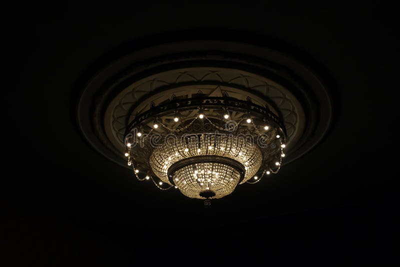 Close-up of a beautiful large crystal chandelier of round shape hanging from the ceiling in the interior against a dark background royalty free stock photos Close-up of a beautiful large crystal chandelier of round shape hanging from the ceiling in the interior against a dark background royalty free stock photos