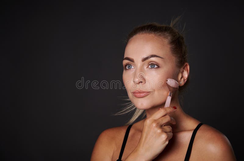 Close Up Of A Beautiful Middle Aged European Woman Massaging Her Face Using A Jade Stone Roller