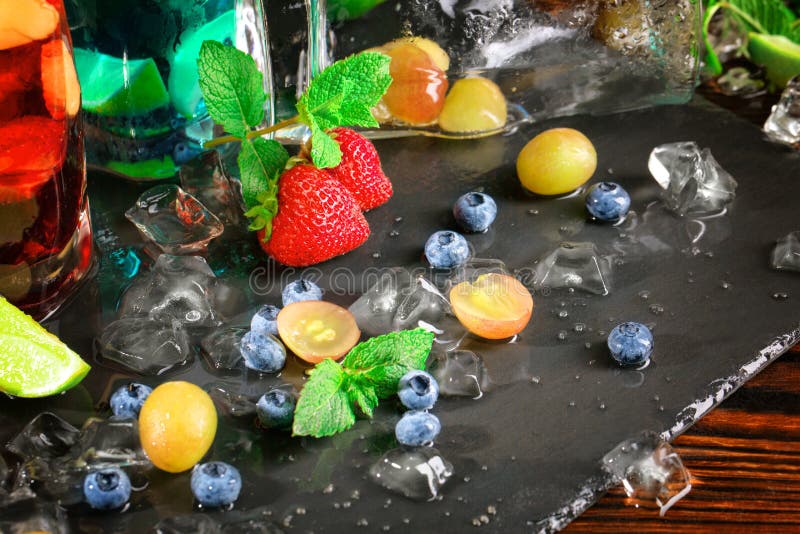 Close-up of beautiful ripe berries with mint. Bright sweet grapes, bilberries and strawberries on the black desk. Copy space.