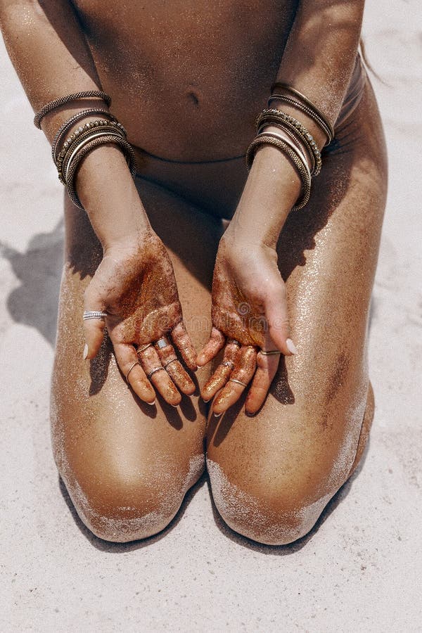 Close up of beautiful young woman in bikini legs and arms with tanned skin on the beach.