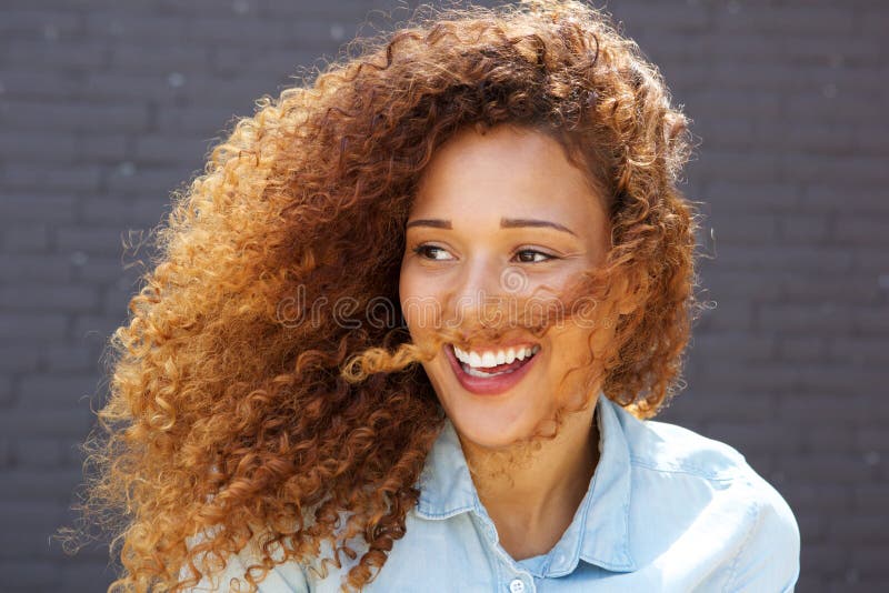 Close up beautiful young woman with curly hair smiling and looking away stock photography Close up beautiful young woman with curly hair smiling and looking away stock photography