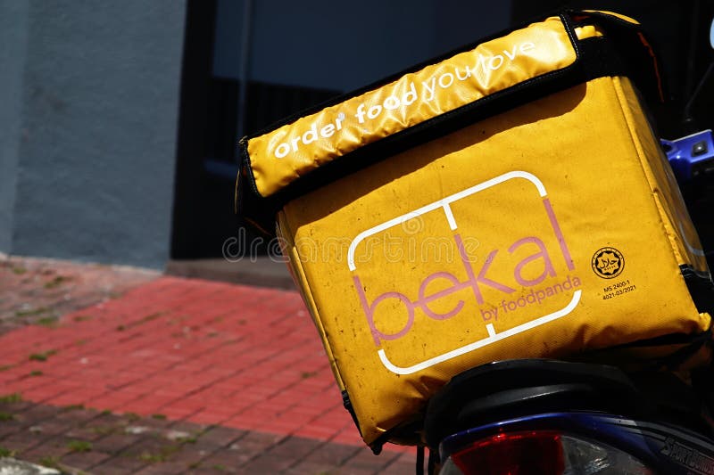 Close-up of the "bekal by foodpanda" thermobag food container placed on the back of a motorbike. Motorbike is parked by the side of the road. bekal is an end-to-end halal-certified by Jakim food delivery service in Malaysia. Close-up of the "bekal by foodpanda" thermobag food container placed on the back of a motorbike. Motorbike is parked by the side of the road. bekal is an end-to-end halal-certified by Jakim food delivery service in Malaysia