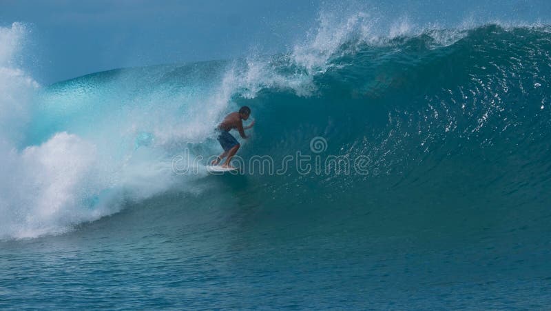 CLOSE UP: Big emerald tube wave curls over an athletic young tourist surfing.