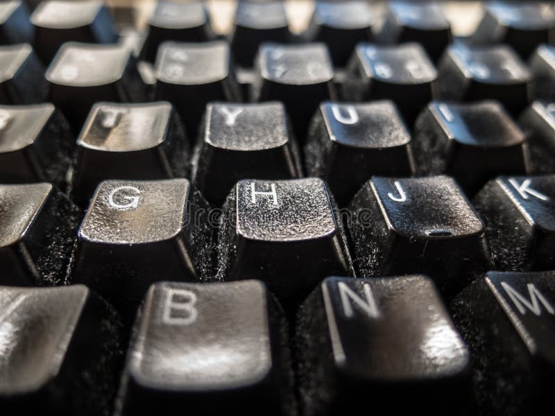 Close-up of black keyboard with shallow depth of field, white letters on every key. Low angel view.