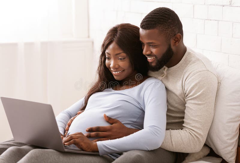 Close up of black pregnant couple using laptop at home