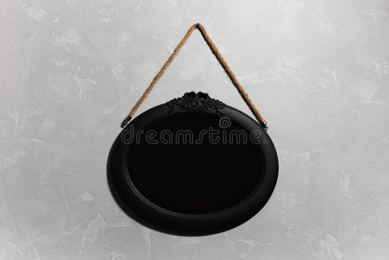Closeup of Black Wooden Mirror Hanging on the Grey Textured Wall