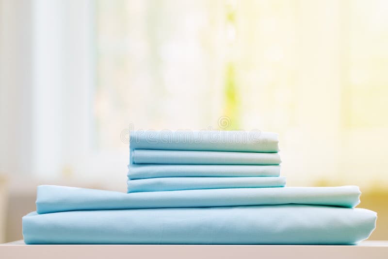 Close-up of blue clean bedding on a blurred background. A stack of folded new bed sheets on the table. stock photo