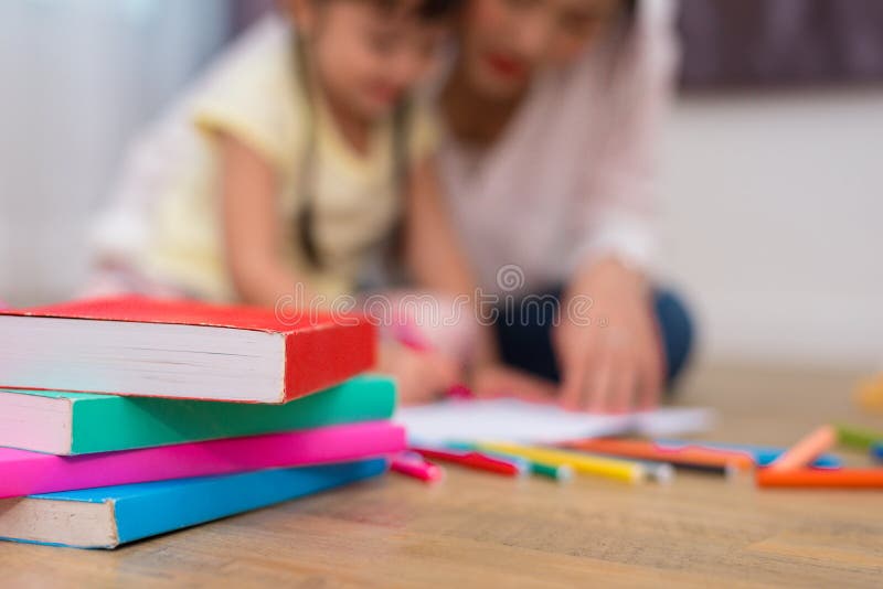 Close up of books and crayon color on floor with mom and kids background. Back to school and Art education learning concept. Children and teacher theme