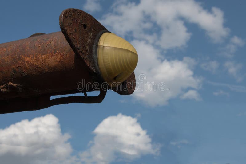 Close-up of the boundary light of an old rusty scraper wagon with blue sky background and clouds stock photo