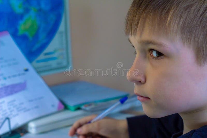 Close-up of boy hand with pencil writing english words by hand on traditional white notepad paper.