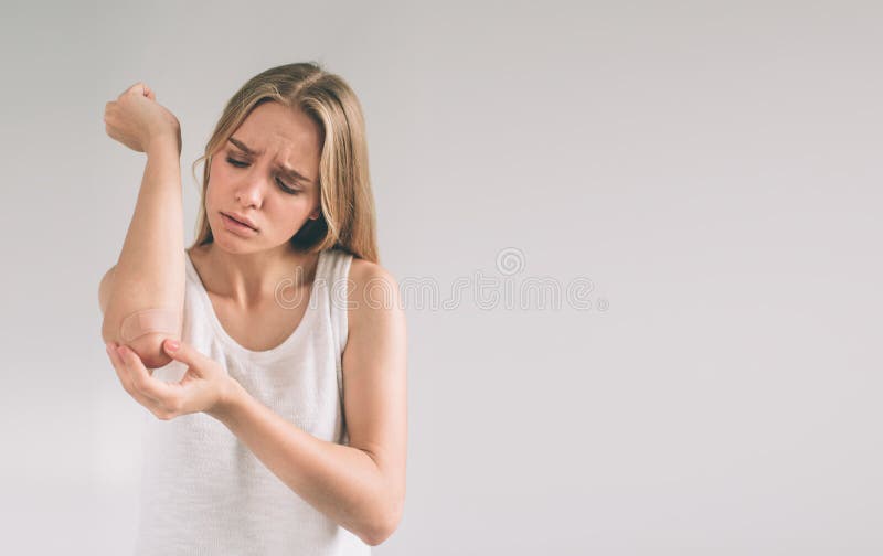 Close up brown bandage or plaster on an injured elbow isolated on white background. Woman applying adhesive bandage stock images Close up brown bandage or plaster on an injured elbow isolated on white background. Woman applying adhesive bandage stock images
